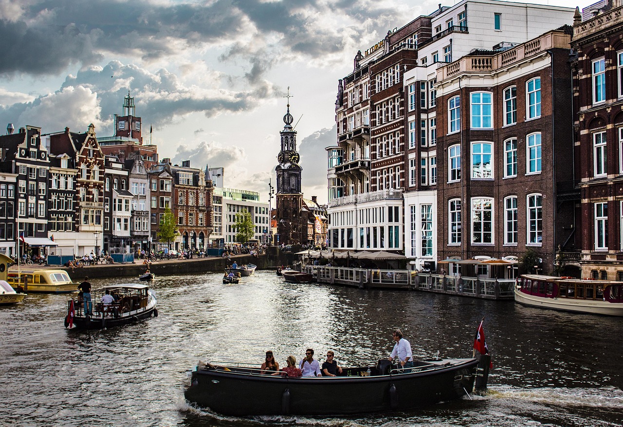 Barco navegando entre casas flotantes en un canal de Ámsterdam